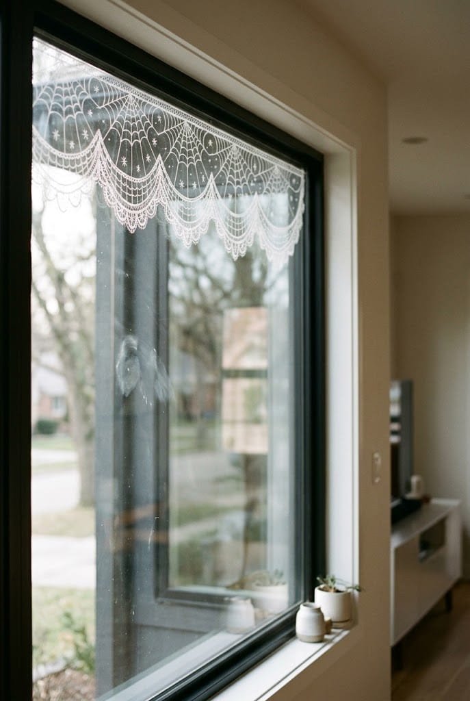 Spiderweb lace valance painted on upper window pane for aesthetic halloween window painting ideas.